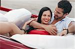 boyfriend and girlfriend lying inside vintage convertible car and hugging. Horizontal shape, side view