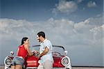 hispanic boyfriend and girlfriend standing near vintage car in havana, cuba. Horizontal shape, side view, copy space