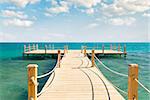 tropical wooden pier in turquoise sea at sunny weather, cloudy skies