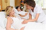 Nurse checking pregnant woman's belly and smiling