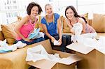 Three girl friends unpacking boxes in new home smiling