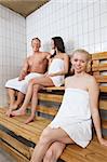 Group of people sitting on bench in a sauna