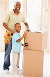 Father wearing tool belt standing by son and boxes in new home s