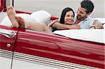 boyfriend and girlfriend lying inside vintage convertible car and hugging. Horizontal shape, full length, side view