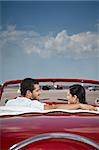 boyfriend and girlfriend sitting in vintage car and hugging in havana, cuba. Vertical shape, rear view, copy space
