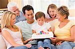 Family in living room smiling with young boy blowing out candles