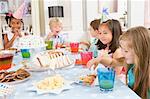 Young children at party sitting at table with food smiling