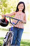Young girl with bicycle outdoors smiling
