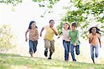 Five young friends running outdoors smiling