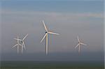 wind power turbines on a hill in fog