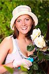 A picture of a young happy woman working in the garden tending roses