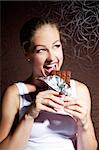 pretty young girl eating chocolate on a dark background