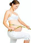 young pregnant woman measuring belly on a white background