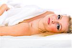 Portrait of sensual young girl with long blonde hair and expressive eyes lying on bed