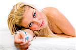 Sensual young girl with long blonde hair and expressive eyes lying on bed