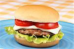 Mini cheese burger with tomato and lettuce on a blue dish