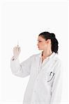 Dark-haired doctor looking at a syringe on a white background