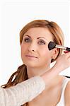 Make-up artist applying make up to an attractive woman in a studio