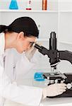 Dark-haired female looking through a microscope in a lab