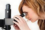 Blond-haired scientist looking through a microscope in a lab