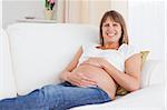 Good looking pregnant woman posing while lying on a sofa in her apartment