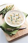 Bowl of asparagus soup with croutons on white background