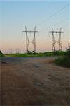 Landscape with high-voltage line over the road. Perspective in warm morning light
