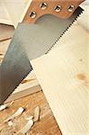 Wood workshop. Hand saw cutting plank.