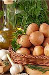 Fresh baby potatoes, garlic, olive oil and spicy herbs on a kitchen board.