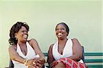 portrait of two happy african adult women talking on bench and smiling. Horizontal shape, copy space