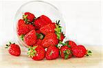 fresh appetizing red strawberries scattered from in glass bowl