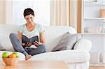 Lovely brunette reading a book in her living room