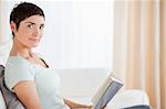 Short-haired woman holding a book while lokking at the camera