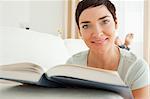 Close up of a short-haired woman with a book looking at the camera