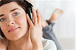 Close up of a brunette listening to music while looking at the camera