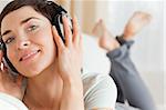 Close up of a smiling brunette listening to music lookig at the camera