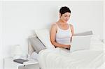 Beautiful woman using a laptop in her bedroom