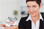 Close up of a brunette showing a miniature house with the camera focus on the object