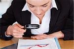 Close up of a woman looking at a chart with a magnifying glass in her office