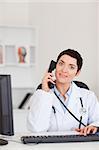 Portrait of a  smiling female doctor making a phone call in her office