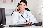 Smiling female doctor making a phone call in her office