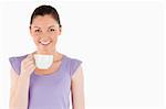 Pretty woman enjoying a cup of coffee while standing against a white background