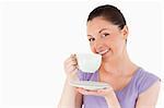 Cute woman enjoying a cup of coffee while standing against a white background