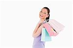 Beautiful woman holding shopping bags while standing against a white background