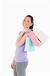 Good looking woman holding shopping bags while standing against a white background