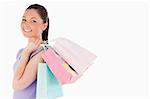 Attractive woman holding shopping bags while standing against a white background