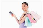 Attractive woman with a credit card holding shopping bags while standing against a white background