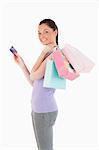 Beautiful woman with a credit card holding shopping bags while standing against a white background