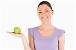 Beautiful woman holding an apple while standing against a white background