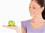 Charming woman holding an apple while standing against a white background